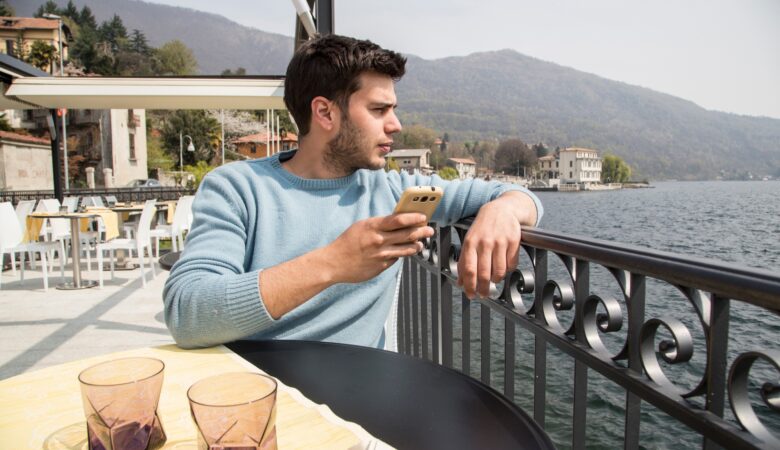 Young man looking out from lakeside restaurant, Lake Mergozzo, Verbania, Piemonte, Italy