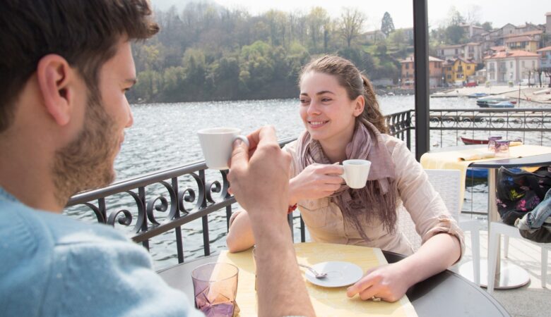 Couple drinking espresso at lakeside restaurant, Lake Mergozzo, Verbania, Piemonte, Italy