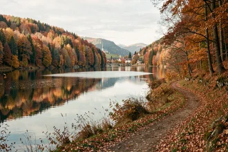 Sentier du tour du lac de Gérardmer en automne avec reflets colorés des Vosges dans l'eau